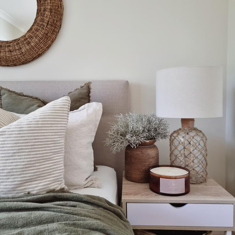 Pepper & Oak Candle sitting on a bedroom side table