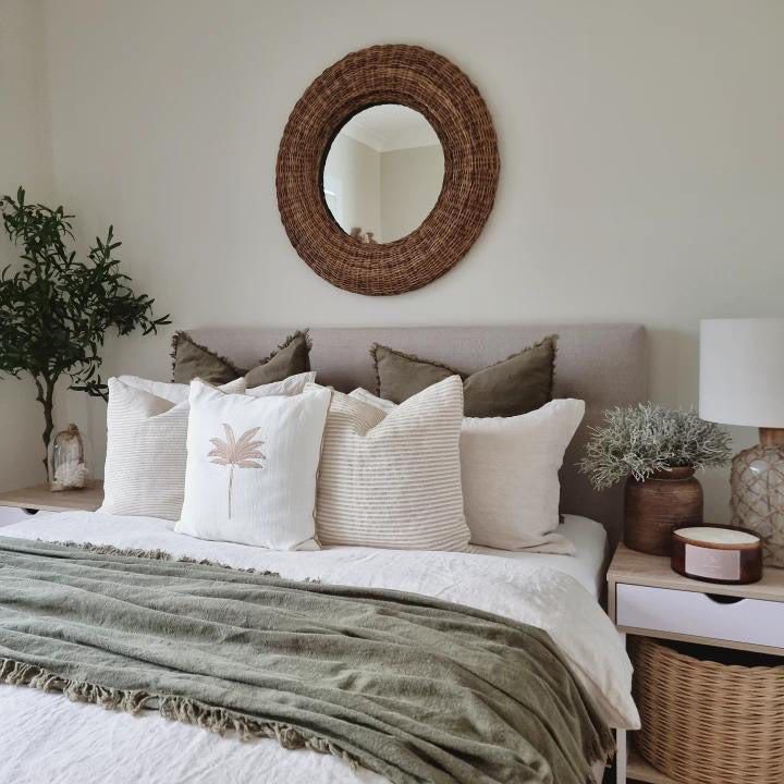 A large candle bowl sitting on a bedside table in a bedroom with green accents and natural feeling